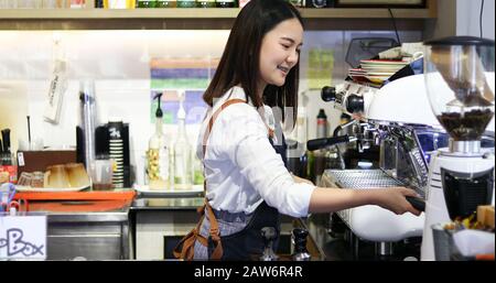 Asian women Barista smiling and using coffee machine in coffee shop counter - Working woman small business owner food and drink cafe concept Stock Photo
