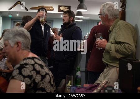 People during a music session at the Colonsay Hotel on the the Inner Hebridean island of Colonsay on Scotland's west coast.  The island is in the council area of Argyll and Bute and has an area of 4,074 hectares (15.7 sq mi). Aligned on a south-west to north-east axis, it measures 8 miles (13 km) in length and reaches 3 miles (4.8 km) at its widest point, in 2019 it had a permanent population of 136 adults and children. Stock Photo