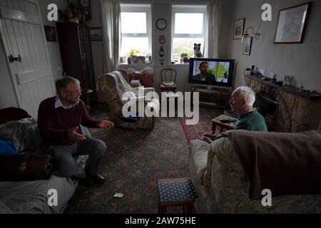 GP Dr David Binnie chatting to patient Walter Williams at his home at Kiloran Bay on the the Inner Hebridean island of Colonsay on Scotland's west coast.  The island is in the council area of Argyll and Bute and has an area of 4,074 hectares (15.7 sq mi). Aligned on a south-west to north-east axis, it measures 8 miles (13 km) in length and reaches 3 miles (4.8 km) at its widest point, in 2019 it had a permanent population of 136 adults and children. Stock Photo