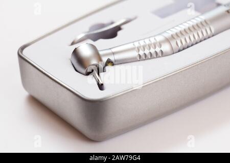High-speed dental handpiece in packing box on white background. Dental instruments for dental treatment. Medical tools. Close-up view. Shallow depth o Stock Photo