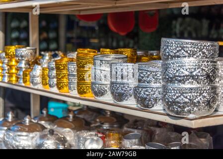 Metal bowls, dishes stacked in one another on display in a row. Traditional Asian bowls in silver and golden metal Stock Photo