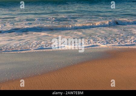 Soft waves with white foam on sandy beach. Tropical summer seaside vacation background Stock Photo