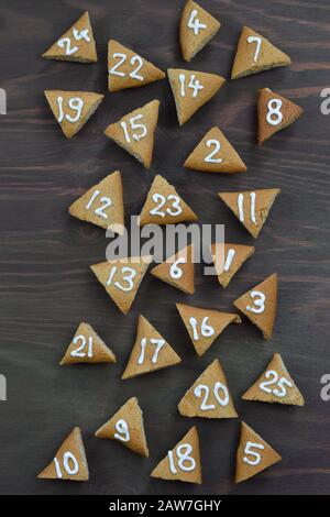 twenty five numbered mingled advent cookies on brown wooden background as advent calendar Stock Photo