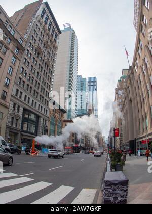 New York City street road in Manhattan. Buildings, steam and skyscrapers. Stock Photo
