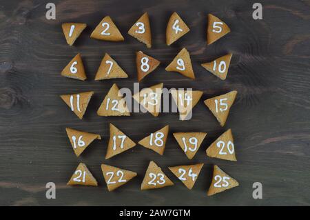 twenty-five numbered and chronological sorted advent cookies on brown wooden background Stock Photo