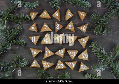 twenty five numbered advent cookies on brown wood with pine boughs Stock Photo