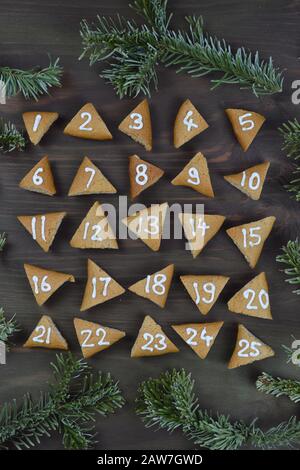 twenty five numbered advent cookies on brown wood with pine boughs Stock Photo