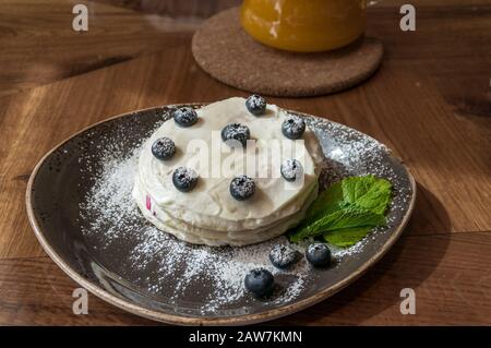 Layered cake with fresh blueberries and green mint leaves on rustic plate Stock Photo