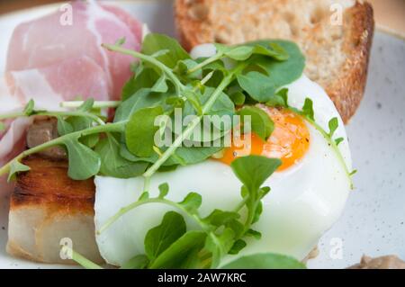 Breakfast of egg with runny yolk on sourdough toast with bacon, pancetta. Breakfast meal close up Stock Photo