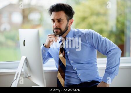 Man sat at computer thoughtful Stock Photo