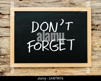 text 'don't forget' on black chalkboard with wooden background. meeting remind reminder note concept Stock Photo