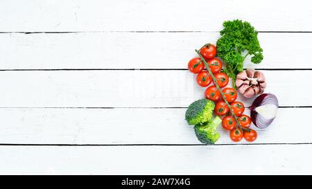 Fresh vegetables on a white wooden background. Avocados, tomatoes, garlic, parsley, paprika. Top view. Free space for your text. Stock Photo