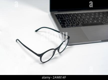 protective glasses on an empty desk with blurred computer screen on background Closeup Stock Photo