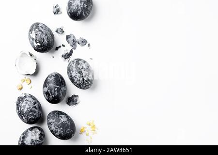 Handmade black textured painted eggs and eggshell on a white background. Happy Easter minimal concept. Copy space, top view, flat lay, horizontal Stock Photo