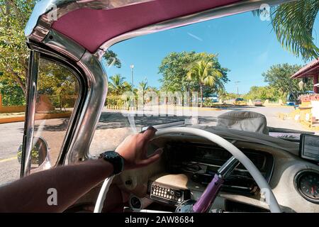 Inside of a vintage pink classic american car in Cuba. driver holds the steering wheel of the old car with his hand. Varadero Stock Photo