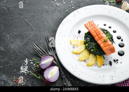 Baked salmon fillet with spinach and apple on a plate. Top view. Free copy space. Stock Photo