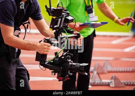 Close-up of videographer shooting with camera standing on the track Stock Photo