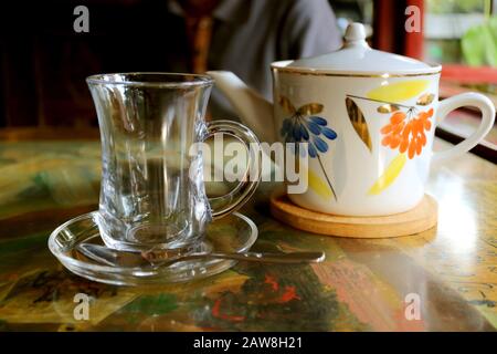 Transparent tea cup with a porcelain teapot on the table Stock Photo