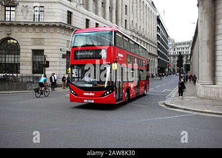 An electric (battery powered) double decker bus passing a cyclist at Bank  in the City of London. And almost no traffic!