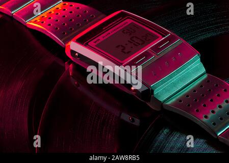 Vintage digital watch lies on multiple vinyl records, blue and red purple light, disco colors, idyllic background, wrist watch, Casio A200 Stock Photo