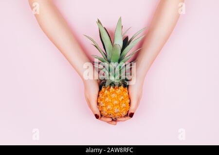 Hands with pineapple on stylish pink background. Stock Photo