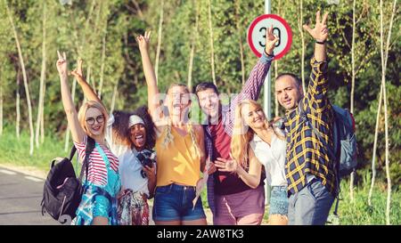 Group of best friends having fun taking selfie with raised arms during travel adventure in countryside Stock Photo