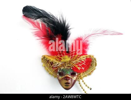 plastic mask in a hat with feathers on a white background top view. Brown masquerade mask in a hat with a red and black feather. Carnival outfit for t Stock Photo