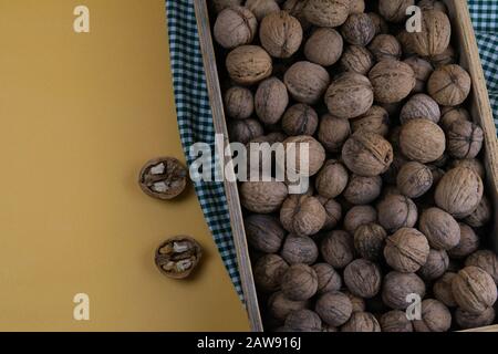 Whole walnuts in shells in a box, walnuts kernels. next to the box is a nut crush. Stock Photo