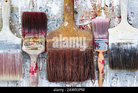 Old used paint brushes on vibrant colourful paint splattered background Stock Photo