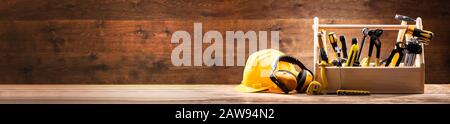 Safety Equipment's Near Toolbox With Various Work Tools On Wooden Surface Stock Photo