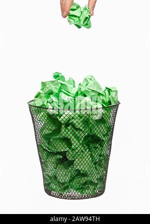 Recycing litter. Hand recycling green waste paper dropping litter into a waste paper basket Stock Photo