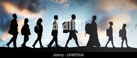 Silhouette Of Refugees People With Luggage Walking In A Row Stock Photo