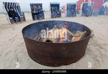 07 February 2020, Mecklenburg-Western Pomerania, Warnemünde: The first visitors came to the start of the Warnemünde winter fun at a fire on the Baltic Sea beach and took a seat in beach chairs. During the three-day event there will be, among other things, beach fires, a parade of riders and an ice bath carnival of the winter swimmers from the association 'Rostocker Seehunde'. Photo: Bernd Wüstneck/dpa-Zentralbild/ZB Stock Photo