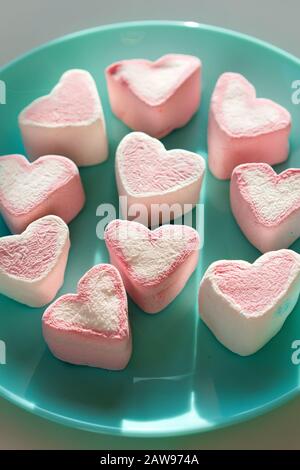 A cup with heart-shaped marshmallows, close-up on a blue wooden background.  Stock Photo by puhimec