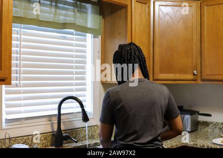 Portrait of an African-American teenaged girl washing dishes at home