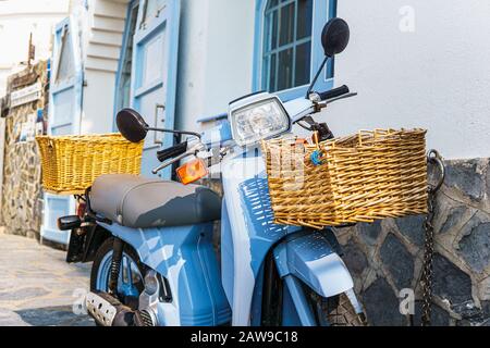 Blue motorbike with wicker baskets on it Stock Photo