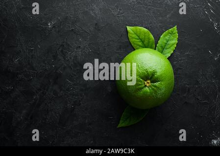 Sweetie green citrus fruit. On a black stone background. Top view. Free copy space. Stock Photo