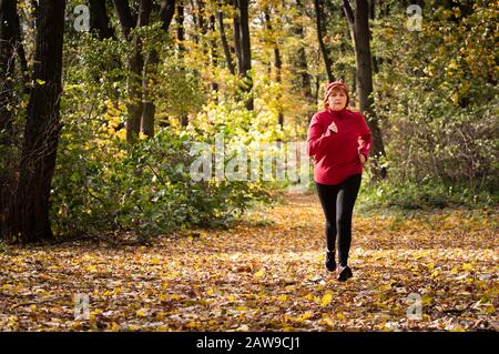 Middle age woman wearing sportswear and running in forest at mountain Stock Photo