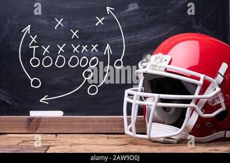 Sport Helmet In Front Of A Chalkboard With Football Play Strategy Stock Photo