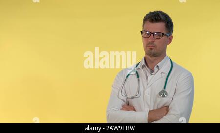 Portrait of young doctor in lab coat denying something to the camera. He is in eyeglasses and with stethoscope on shoulders. Stock Photo