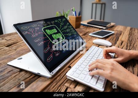 Businesswoman Working On Laptop Making Mind Map At Wooden Desk Stock Photo
