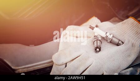 Spark plug. Car candles lie on gloves, in background service center Stock Photo