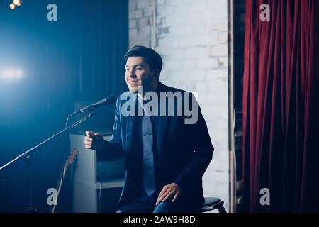 Stand up comedian on stage. Young man talks joke into microphone or sings songs. Stock Photo