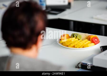 Shallow depth of field (selective focus) image with various fruits cut into pieces on a plate on a white table. Stock Photo