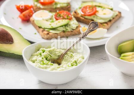 Avocado spread guacamole toasts egg tomato chives as breakfast meal or appetizer Stock Photo