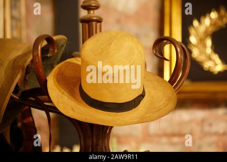 Old yellow linen sun hat hanged on a wooden cloth hanger Stock Photo