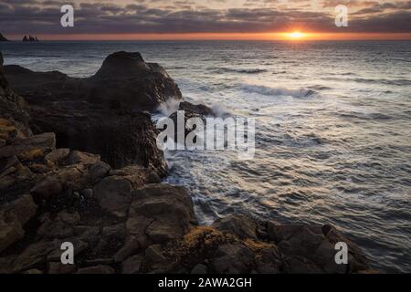 Dyrholaey lighthouse over black sand beach in Iceland Stock Photo