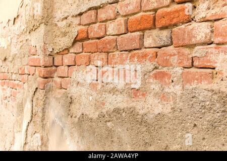 Peeled plaster on an old brick wall. Broken wall. Red bricks in old wall. Detail of wall. Stock Photo
