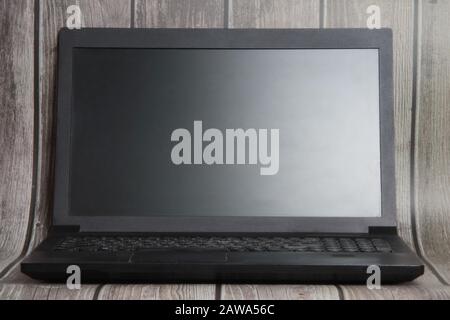 A laptop with a empty screen stands on the background of wooden boards. Place for text, layout for design. Stock Photo