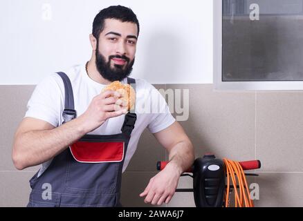 Worker wearing uniform eating burger during a lunch break Stock Photo